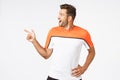 Excited, happy amused masculine sportsman in activewear, attend gym, pointing turning left astonished, gasping from