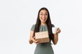 Excited happy asian woman drinking coffee and receive home delivery, holding box package with cheerful smile, finally