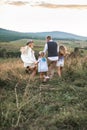 Excited happy Cauasian family enjoy while running in green summer field at sunset. Pretty young mother woman turning Royalty Free Stock Photo