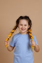 Excited happy cheerful little girl smiling with missing tooth looking at camera holding kanekalon braids with hands on Royalty Free Stock Photo