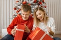 Excited happy couple opening Christmas gifts at home sitting on the floor near Xmas tree Royalty Free Stock Photo