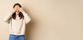 Excited happy girl smiling, close eyse and wait for surprise gift, standing blinsided over beige background