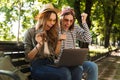 Excited happy ladies friends outdoors sitting using laptop computer. Royalty Free Stock Photo