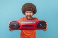 Excited happy man holding out red tape recorder, enjoying listening to tapes. Royalty Free Stock Photo