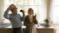 Excited happy mature family couple singing at utensils Royalty Free Stock Photo