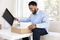 Excited happy young Black consumer man opening cardboard box Royalty Free Stock Photo