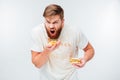 Excited hungry bearded man greedily eating hamburgers