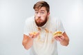 Excited hungry bearded man greedily eating hamburgers