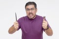 An excited, hungry man holding a knife and fork with an eager expression, ready for a delicious meal. Looking a bit angry from