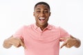 Excited and impressed happy african american man standing high pointing down with amazed and cheerful expression