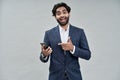 Excited indian business man pointing at mobile phone isolated on beige.