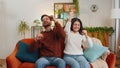 Excited Indian couple dancing, moving to rhythm, dabbing raising hands, making dub dance gesture