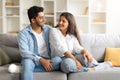 Excited Indian spouses laughing and relaxing on a sofa