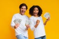 Excited interracial couple holding lot of dollar cash, celebrating success together Royalty Free Stock Photo