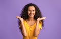 Excited joyful brunette jumping with raised hands over purple background
