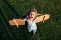 Excited kid with backpack wings. Child playing pilot aviator and dreams outdoors in park. Smiling kid dreaming about