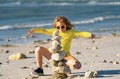 Excited kid boy playing with stones on the beach. Child play with pyramid of stones on the beach, sea seascape, rest and Royalty Free Stock Photo