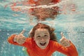 Excited kid boy with thumbs up swim and dive underwater, kid with fun in pool under water. Active healthy lifestyle Royalty Free Stock Photo