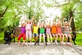 Excited kids with arms and sit in row on bench