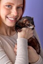 excited lady posing with ferret isolated in studio on purple background, cute domestic animal Royalty Free Stock Photo