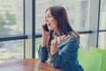 Excited laughing pretty woman sitting in a cafe, she is talking on phone and gossiping with her best friend. Emotion expressing ca Royalty Free Stock Photo