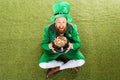 Excited leprechaun with pot of gold sitting