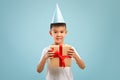 Excited little asian birthday boy wearing party hat holding wrapped gift box Royalty Free Stock Photo