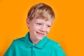 Excited little blond boy laughing and looking away on yellow background Royalty Free Stock Photo