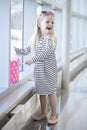 Excited little blond-haired girl standing with shopping bag Royalty Free Stock Photo