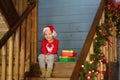 Excited little boy with a Christmas gift on staircase in house. Portrait of happy kid in Christmas morning Royalty Free Stock Photo