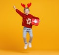 Excited little boy in Christmas sweater and deer antlers jumping up in air with Xmas gift box Royalty Free Stock Photo