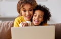 Happy afro american family mother and son watching funny videos on laptop while relaxing in living room at home Royalty Free Stock Photo