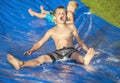 Excited little boys playing on a slip and slide outdoors Royalty Free Stock Photo