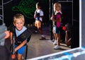 Excited little boy aiming laser gun at other players during lasertag game in dark room Royalty Free Stock Photo