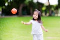 Excited little cute girl playing orange ball on soccer field outdoors. Royalty Free Stock Photo