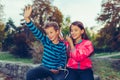 Excited little girl and boy dancing, singing and listening music together with headphones and smart phone outdoor Royalty Free Stock Photo