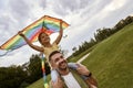 Excited little girl sitting on shoulders of her father and playing with colorful kite, daughter and daddy spending time Royalty Free Stock Photo