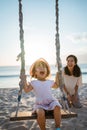 happy Little girl and mother swinging at the beach Royalty Free Stock Photo
