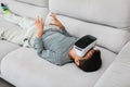 Excited little kid using virtual reality glasses. He lying on gray sofa and using new gadget technology Royalty Free Stock Photo