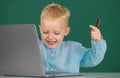 Excited little student boy using laptop computer in school class. Genius child programming, computer training. Royalty Free Stock Photo