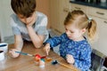 Excited little toddler girl and older brother, school kid boy coloring eggs for Easter. Two cute children, siblings Royalty Free Stock Photo