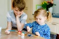 Excited little toddler girl and older brother, school kid boy coloring eggs for Easter. Two cute children, siblings Royalty Free Stock Photo