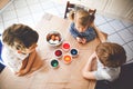 Excited little toddler girl and two kids boys coloring eggs for Easter. Three children, siblings looking surprised at Royalty Free Stock Photo