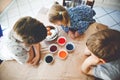 Excited little toddler girl and two kids boys coloring eggs for Easter. Three children, siblings looking surprised at Royalty Free Stock Photo