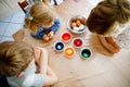 Excited little toddler girl and two kids boys coloring eggs for Easter. Three children, siblings looking surprised at Royalty Free Stock Photo