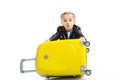 Excited little tourist holding yellow wheel suitcase