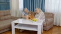 Excited child girl kid involved in build blocks board game with senior grandmother and grandfather
