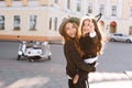 Excited long-haired girl hanging out with little sister wearing trendy black jeans and hair accessory. Portrait of Royalty Free Stock Photo