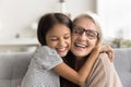 Excited granddaughter kid and happy caring grandmother hugging on couch Royalty Free Stock Photo