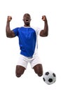 Excited male african american soccer player kneeling while celebrating goal over white background Royalty Free Stock Photo